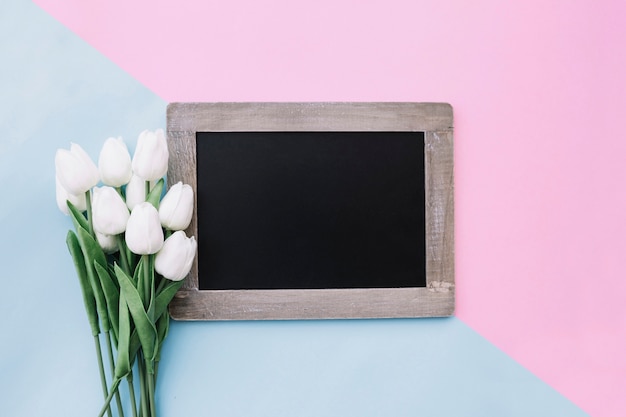 Tafel mit blumenstrauß von tulpen auf rosa und hellblauem hintergrund