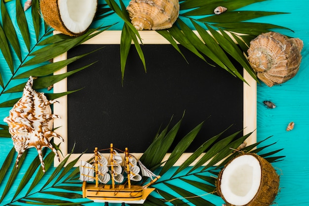Tafel mit Pflanzenblättern und Kokosnüssen in der Nähe von Muscheln