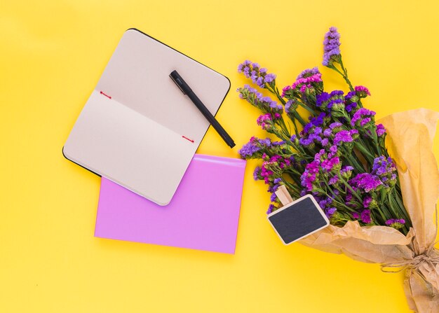 Tafelbeschriftung; lilane Blumen; Tagebuch und Stift auf gelbem Hintergrund