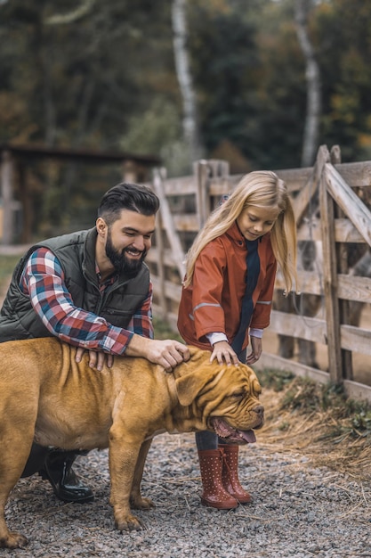 Tag auf dem bauernhof bauer und seine tochter streicheln ihren hund