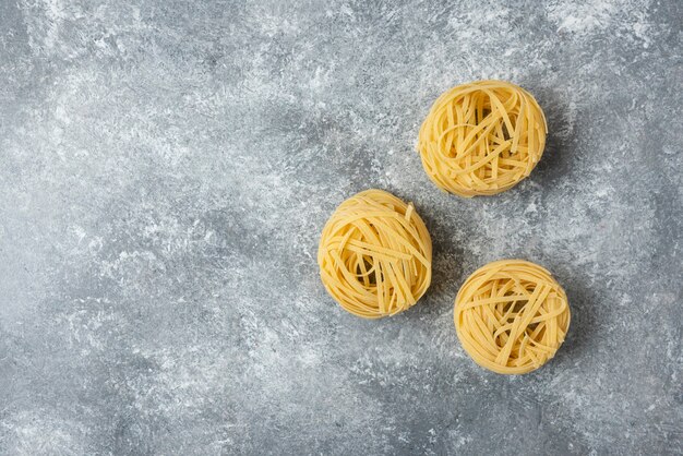 Tagliatelle rohe Nudelnester lokalisiert auf Marmorhintergrund.