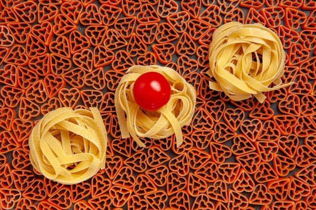 Tagliatelle von oben auf herzförmiger italienischer Pasta-Kirschtomate