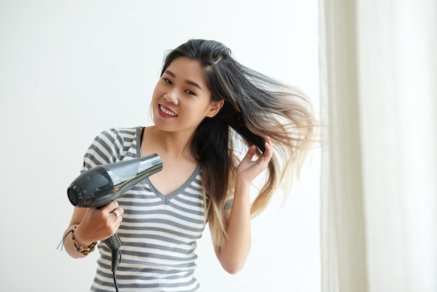 Taille herauf Schuss des asiatischen Mädchens ihr Haar zu Hause föhnend