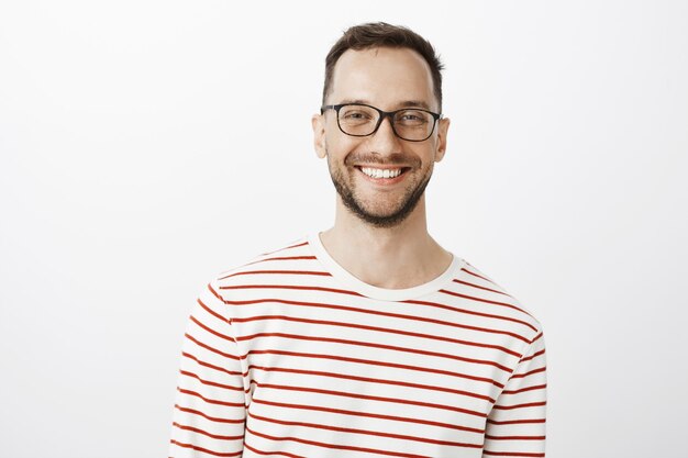 Taillenschuss eines entspannten, gut aussehenden, positiven Mannes in einer Brille, der breit lächelt