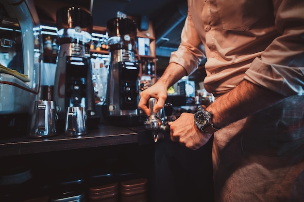 Talentierter Barista bereitet Kaffee für Kunden im noblen Restaurant mit Kaffeemaschine zu.