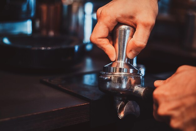 Talentierter Barista bereitet Kaffee für Kunden im noblen Restaurant mit Kaffeemaschine zu.