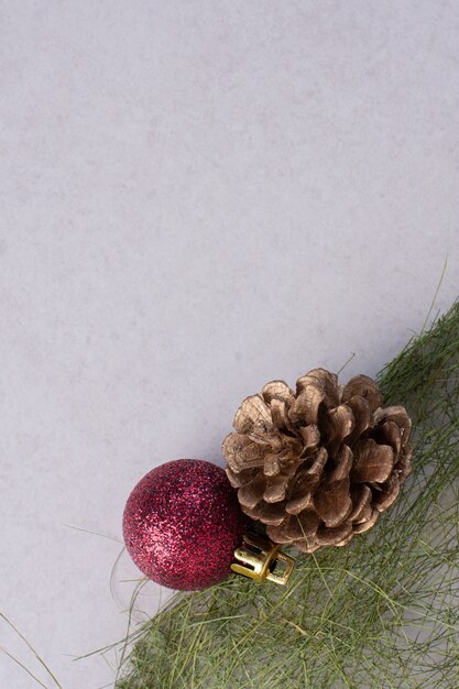 Tannenzapfen mit Weihnachtskugel auf weißer Oberfläche