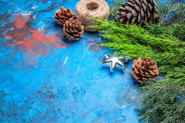 Tannenzweige mit Tannenzapfen-Strohfaden auf blau-rotem Hintergrund freier Raum