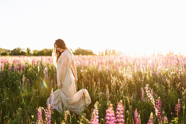 Tanzen der jungen Frau auf einem Wildflowerfeld mit Sonnenaufgang auf dem Hintergrund.