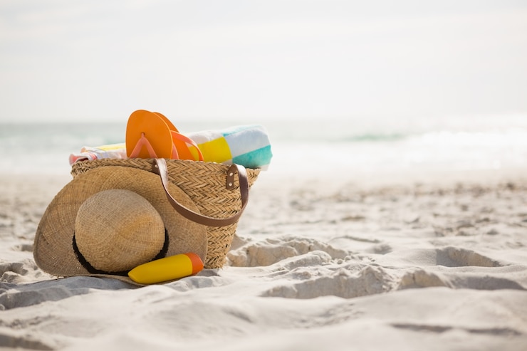 Kostenlose Foto tasche mit strandaccessoires, die auf sand gehalten wird