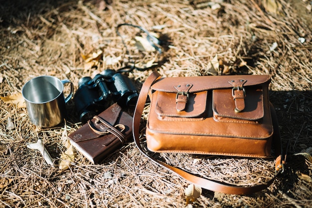 Tasche und Fernglas auf Laub