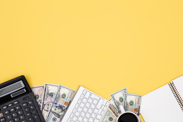 Taschenrechner Geld Notizblock und Tastatur auf gelbem Hintergrund flach liegen
