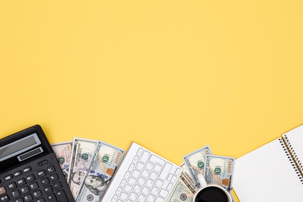 Taschenrechner Geld Notizblock und Tastatur auf gelbem Hintergrund flach liegen
