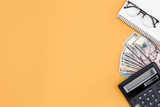 Taschenrechnergeld und Notizblock auf einem orangefarbenen Hintergrund kopieren Raum