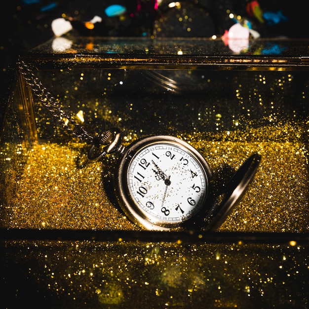 Kostenloses Foto taschenuhr zwischen goldenen glitzern