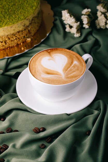 Tasse Cappuccino mit Kaffeebohnen und Kuchen auf dem Tisch