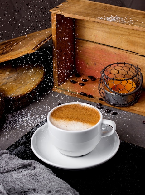 Kostenloses Foto tasse cappuccino und kerze in der holzkiste auf dem tisch