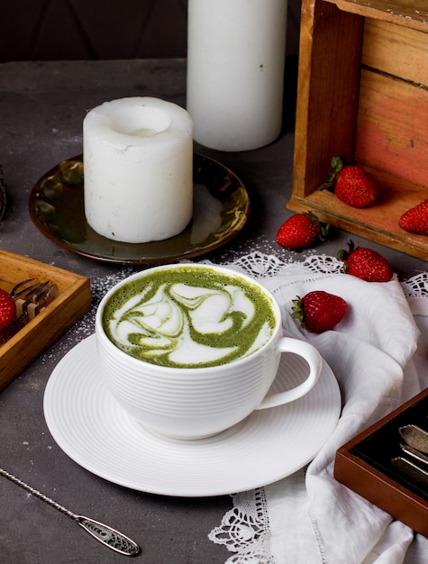 Tasse grüner Kaffee und Erdbeeren auf dem Tisch