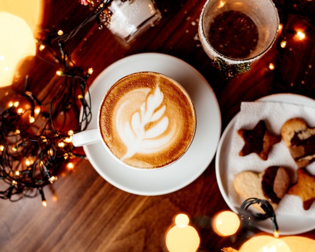 Tasse heißen Cappuccino und eine Platte mit Keksen Draufsicht