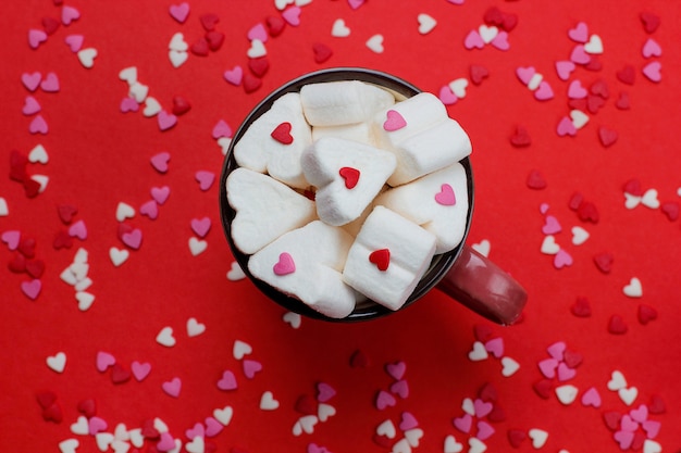 Kostenloses Foto tasse heißen kaffee mit herzförmigen marshmallows und süßigkeiten auf rot