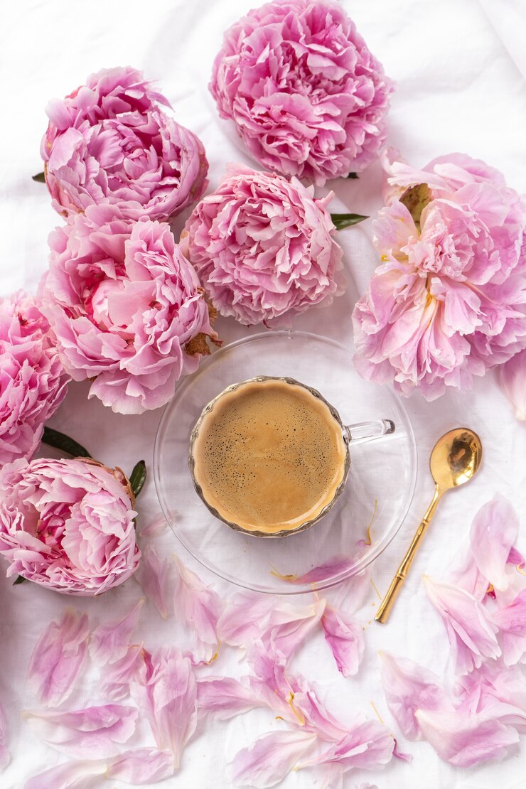 Kostenlose Foto tasse instantkaffee auf dem tisch mit rosa pfingstrosen unter den lichtern