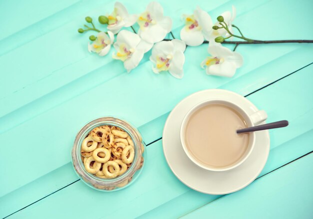 Tasse Kaffee auf altem Holztisch mit frischen Frühlingsblumen und großem Teller mit russischen Bubliks