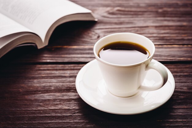 Tasse Kaffee auf einem Holztisch und ein Buch