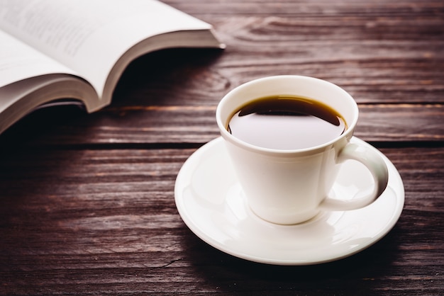 Tasse Kaffee auf einem Holztisch und ein Buch