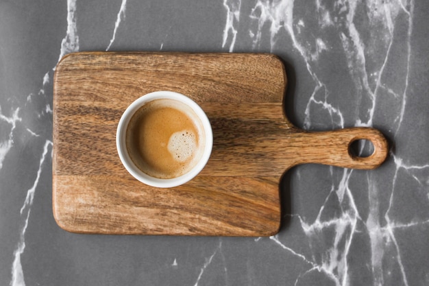 Tasse Kaffee auf hackendem Brett über grauem Marmorhintergrund
