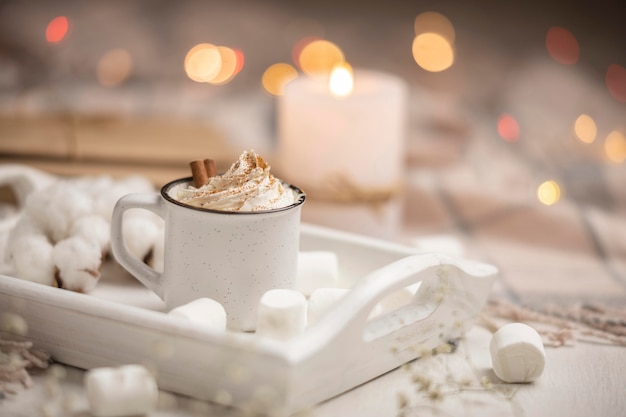 Tasse Kaffee auf Tablett mit Marshmallows und Zimtstangen