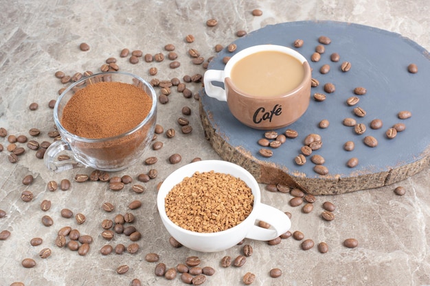 Tasse Kaffee, Kaffeebohnen und gemahlener Kaffee auf Marmoroberfläche. Foto in hoher Qualität