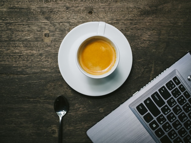 Tasse Kaffee mit einem Laptop Nahaufnahme auf einem Holztisch