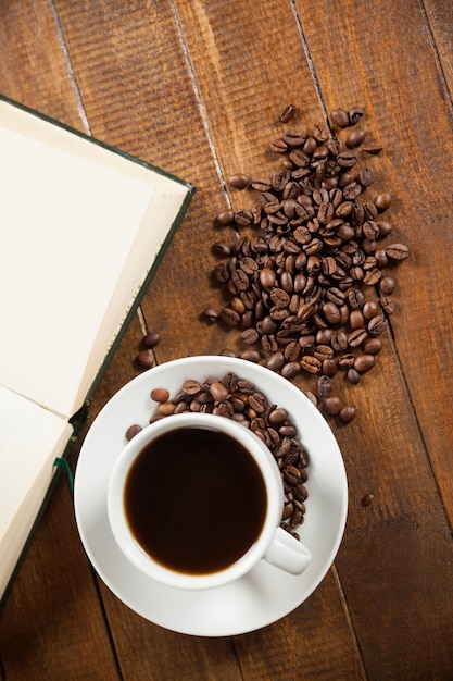 Tasse Kaffee mit Kaffeebohnen und Buch