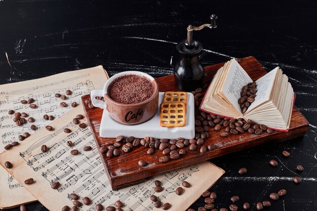 Tasse Kaffee mit Keksen auf einem Holzbrett.
