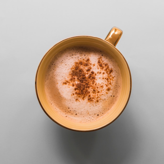 Tasse Kaffee mit Milchschaum und Kakaopulver auf grauem Hintergrund
