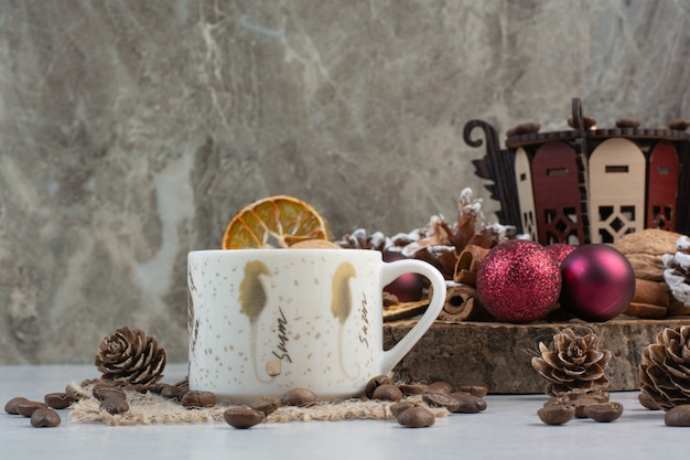 Tasse Kaffee mit Tannenzapfen und Weihnachtskugeln auf Holzteller. Hochwertiges Foto