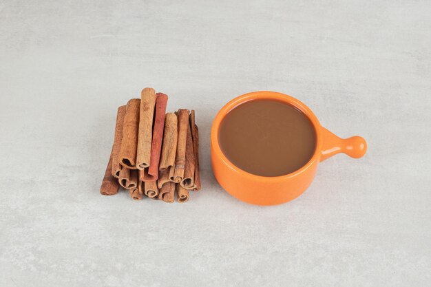 Tasse Kaffee mit Zimtstange auf Marmoroberfläche.