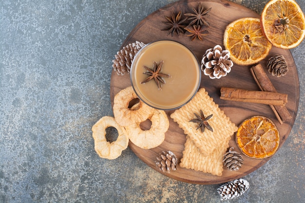 Tasse Kaffee mit Zimtstangen und Tannenzapfen auf Holzteller. Hochwertiges Foto