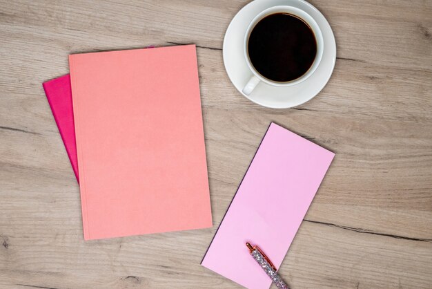 Tasse Kaffee, rosa Notizbuch und Stift