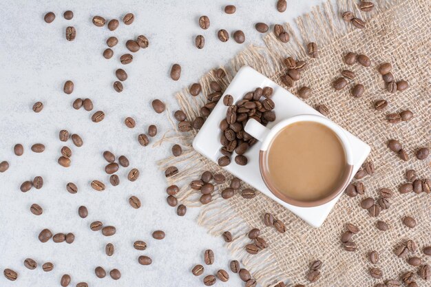 Tasse Kaffee und Kaffeebohnen auf Sackleinen.