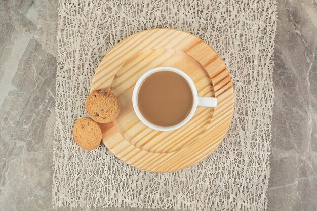 Tasse Kaffee und Kekse auf Holzteller.