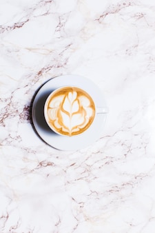 Tasse latte-art-kaffee mit blume auf marmortisch