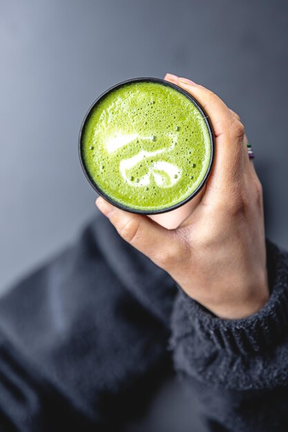 Tasse Matcha-Grüntee in Frauenhand, Draufsicht