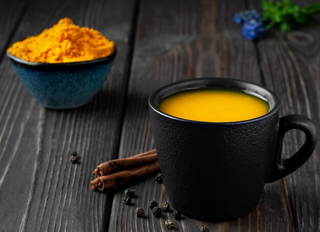 Tasse mit natürlichem gesundem Kräutertee aus Kurkuma, Honig und Gewürzen