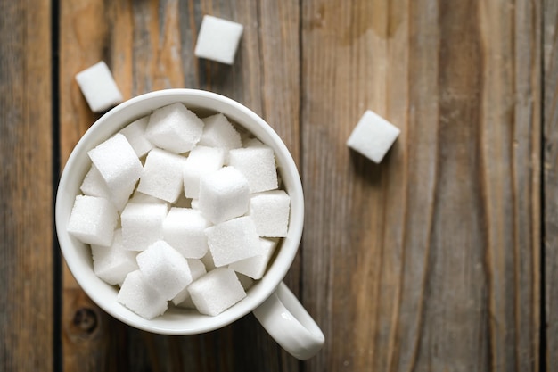 Tasse mit Zuckerwürfeln auf einer Holzoberfläche in Nahaufnahme