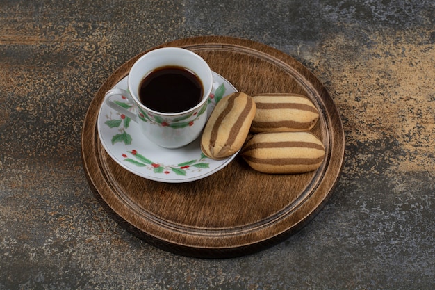 Tasse schwarzen Kaffee mit Keksen auf Marmoroberfläche.