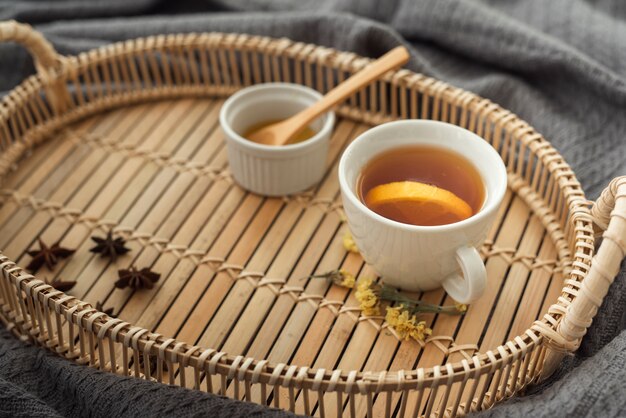 Tasse Tee auf hölzernem Behälter mit Honig