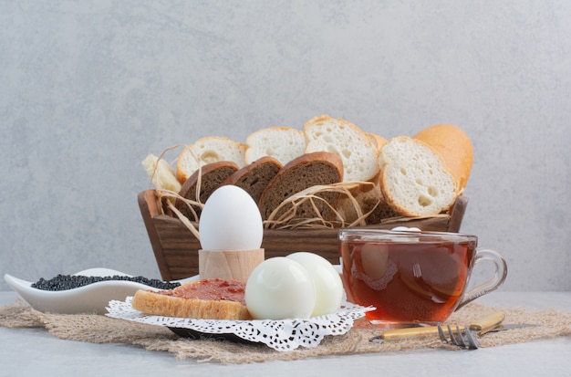 Tasse Tee mit Brot und Eiern auf Sackleinen.