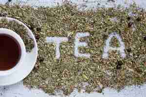 Kostenloses Foto tasse tee mit dem wort tea in trockenen kräutern geschrieben