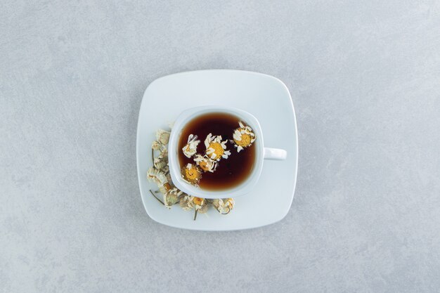 Tasse Tee mit getrockneten Kamillenblüten.